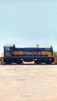 The first JDH switch engine train on the track. It's navy blue with yellow stripes and says J. D. Heiskell and Co., Inc.